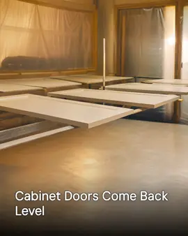 Generated post: refinished cabinet doors laid flat on drying racks in a masked spray room, headline about doors coming back level baked into the image